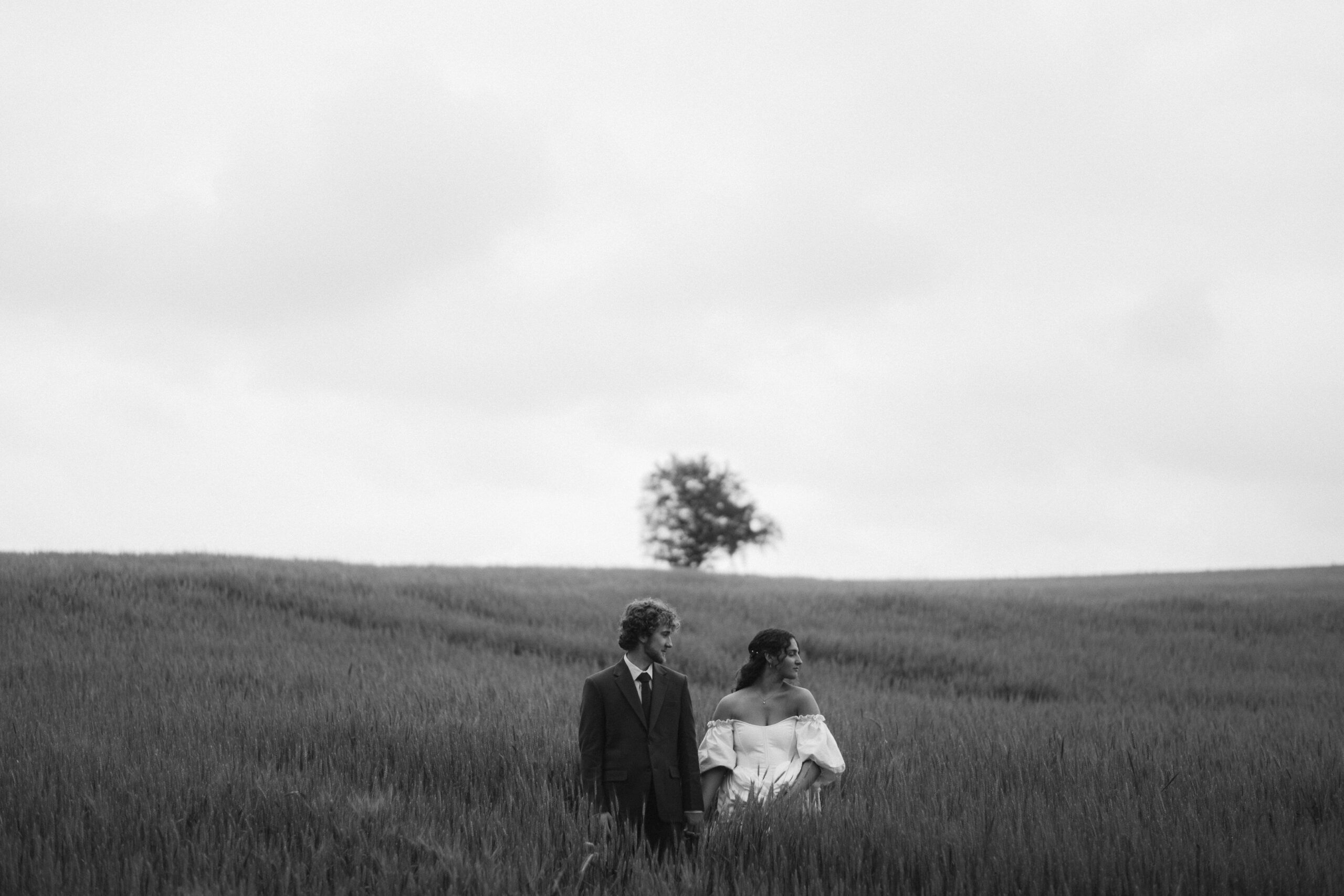 moody black and white portrait of a bride and groom in a field